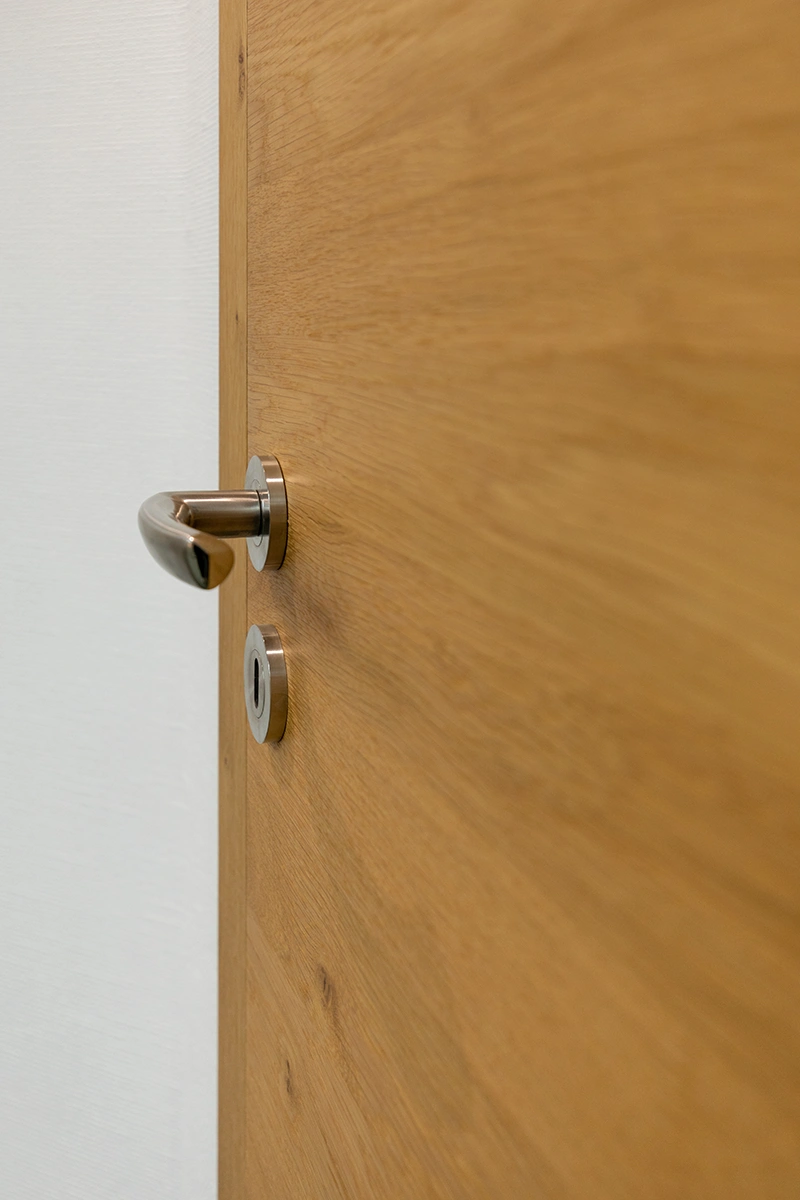 türen - Stumpfeinschlagende Echtholztür ohne sichtbare Falz mit moderner Edelstahl-Drückergarnitur