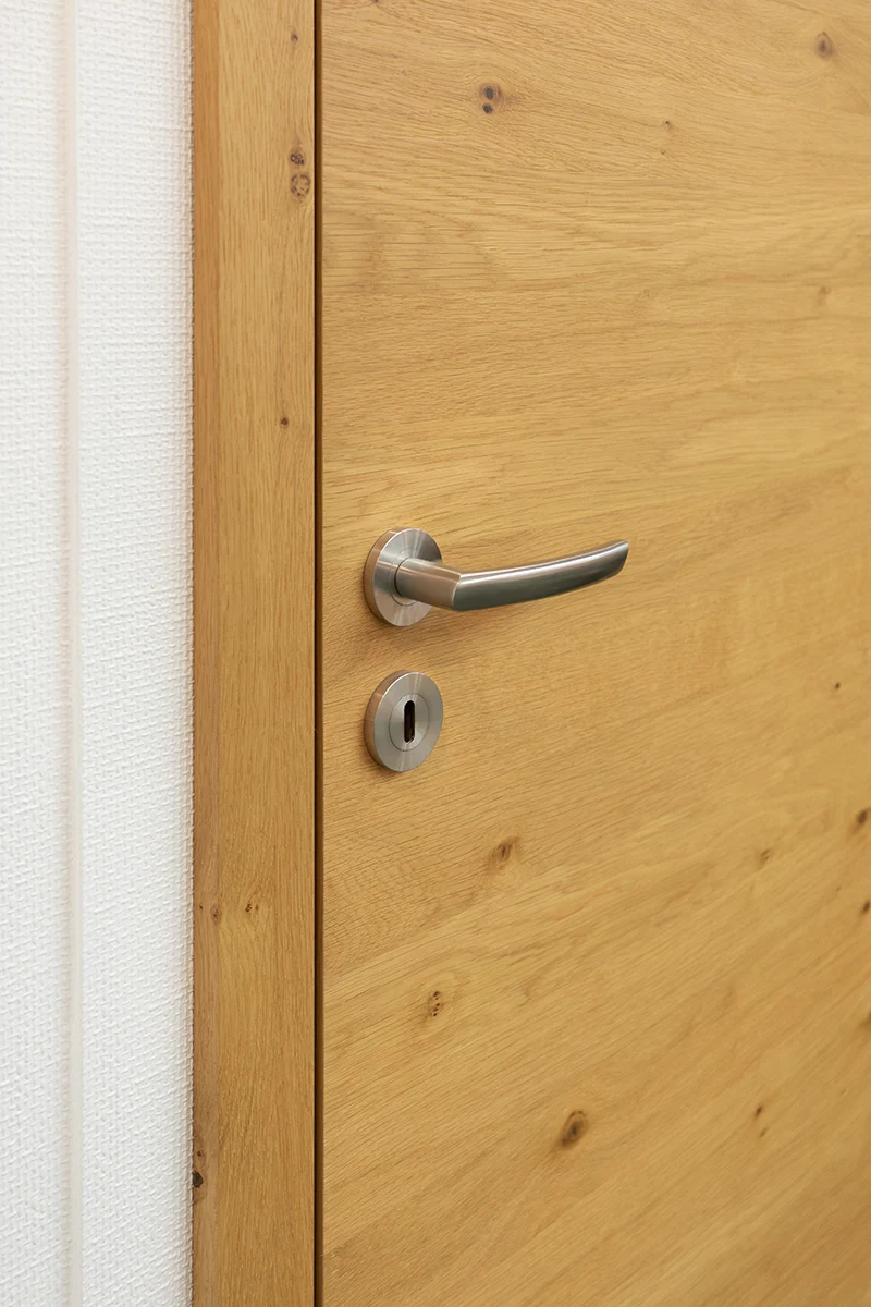 türen - Stumpfeinschlagende Echtholztür ohne sichtbare Falz mit moderner Edelstahl-Drückergarnitur