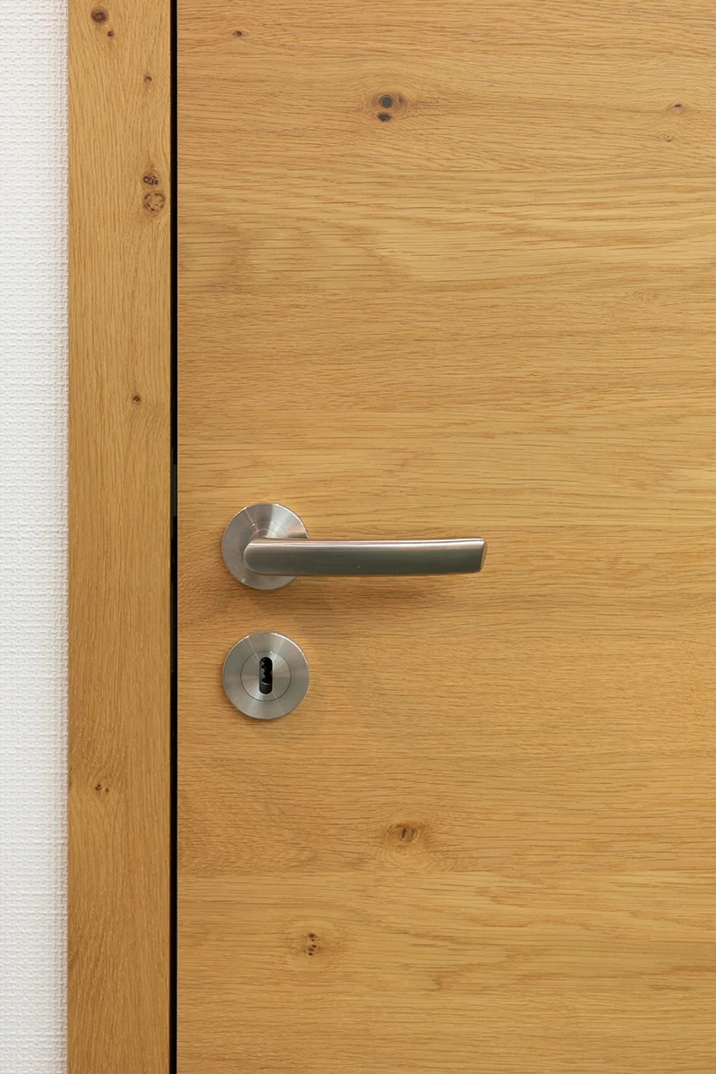 türen - Stumpfeinschlagende Echtholztür ohne sichtbare Falz mit moderner Edelstahl-Drückergarnitur